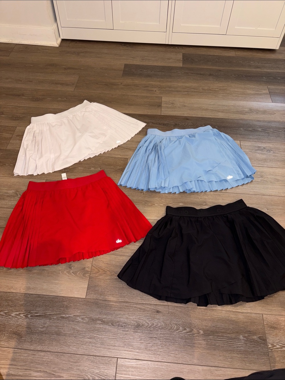 ALO Yoga Pleated Mini Skirt Set in Red, Black, White, and Light Blue lot.